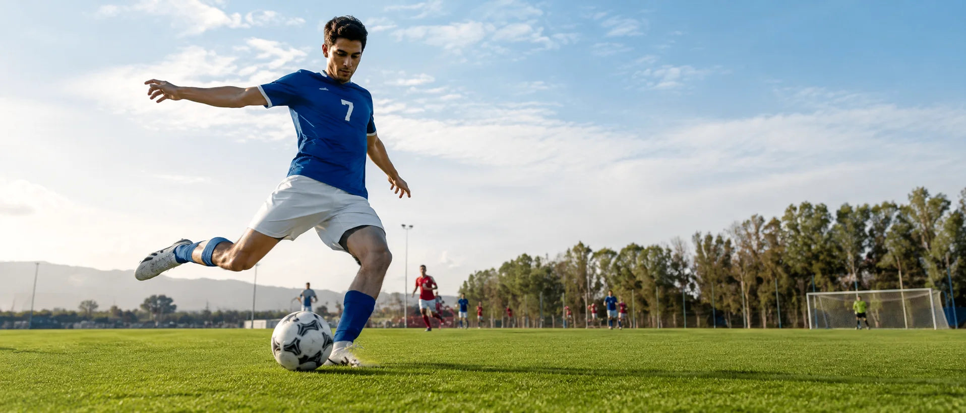 Football player kicking a ball on an outdoor pitch